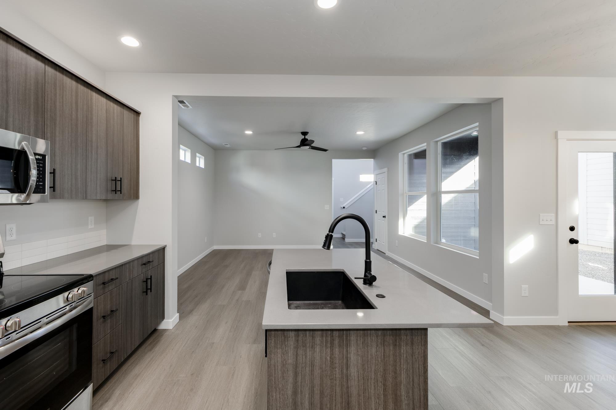 Kitchen with appliances with stainless steel finishes, modern cabinets, ceiling fan, a center island with sink, and light wood-style floors