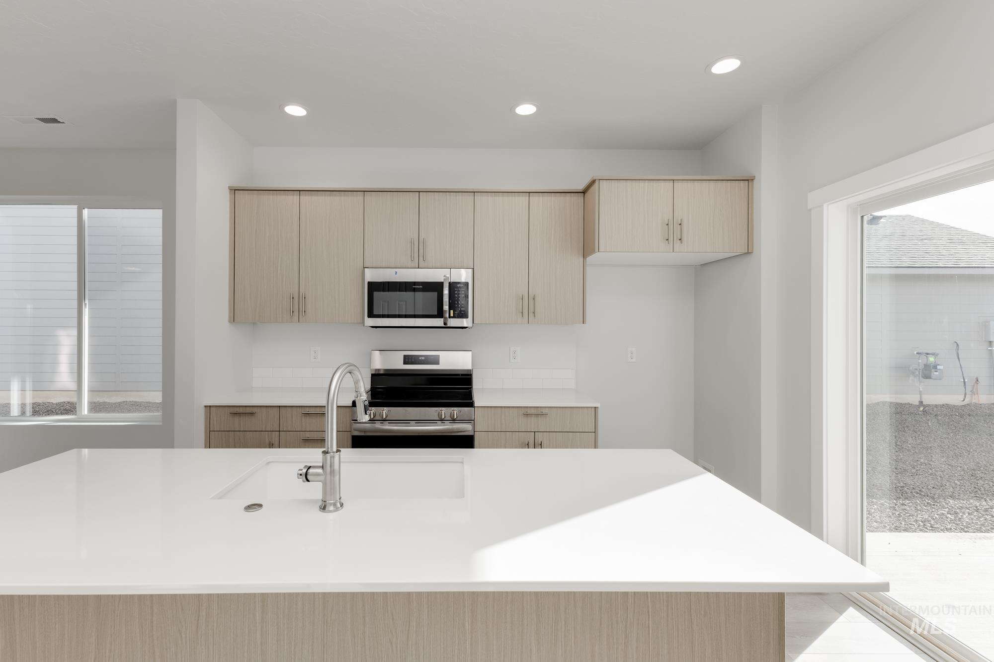 Kitchen featuring light brown cabinetry, healthy amount of natural light, stainless steel appliances, and recessed lighting