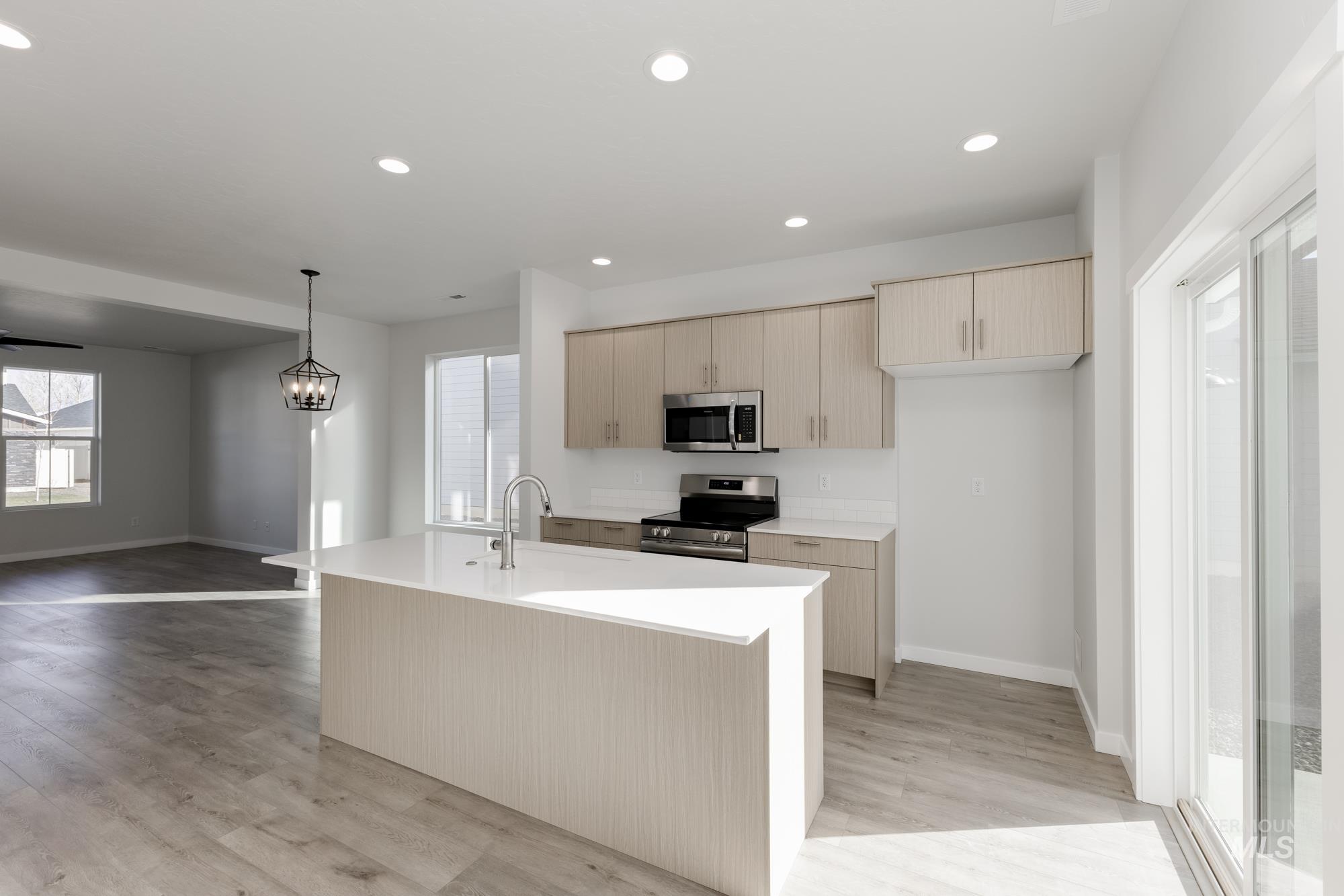Kitchen featuring light brown cabinets, stainless steel appliances, pendant lighting, recessed lighting, and open floor plan