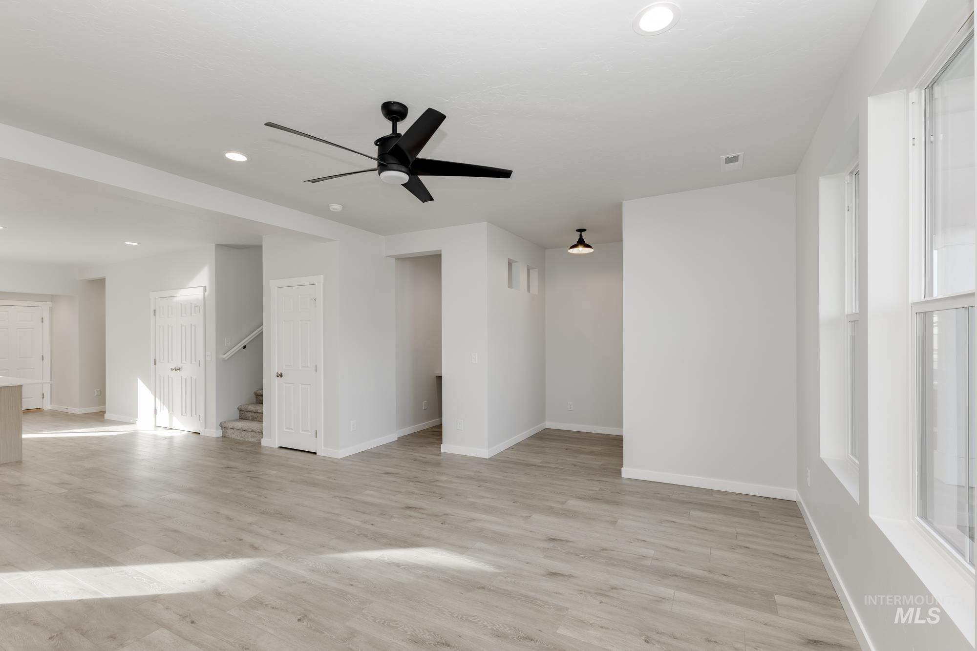 Unfurnished room with ceiling fan, recessed lighting, light wood-type flooring, and stairs