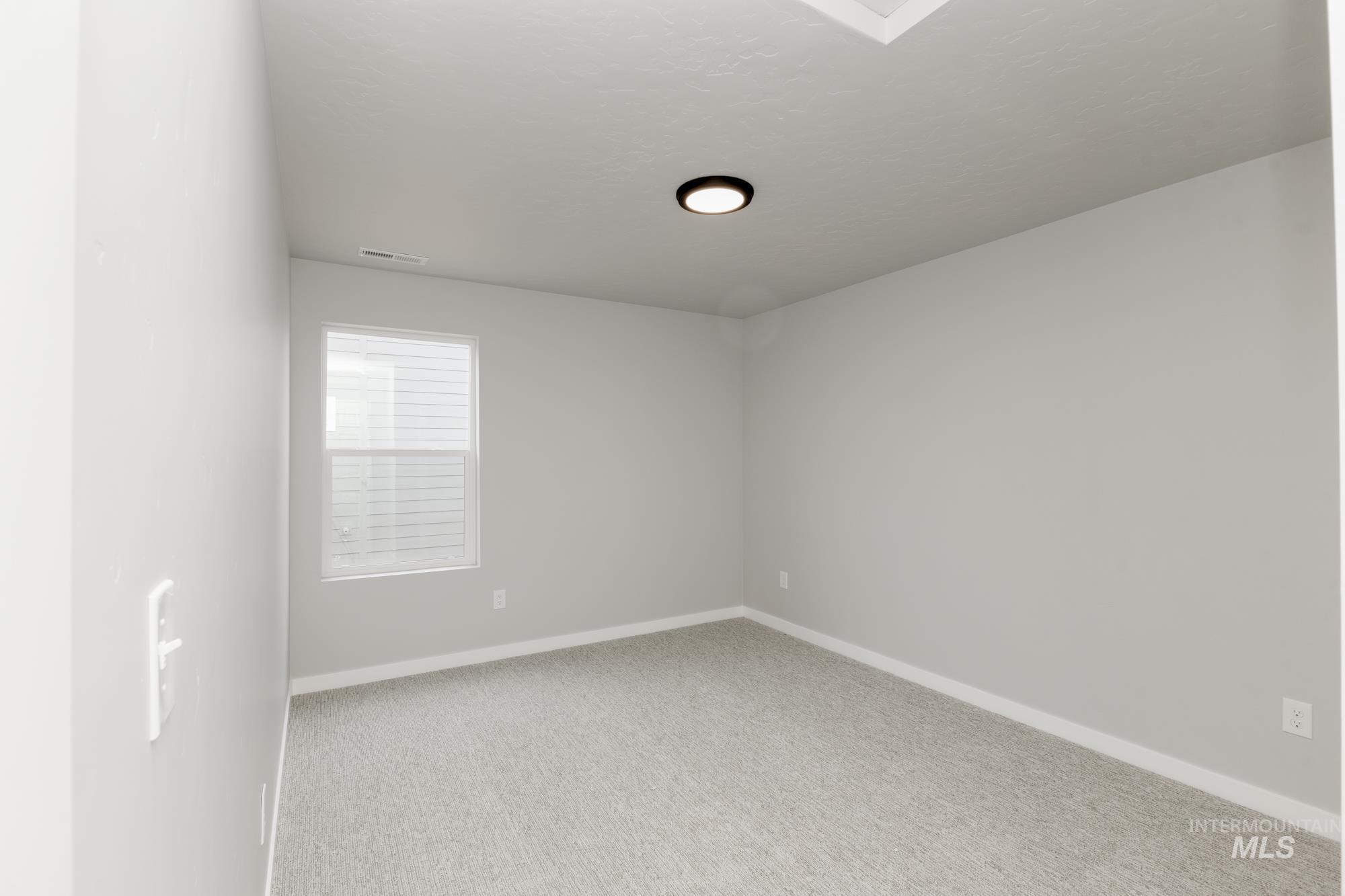 Carpeted spare room featuring baseboards