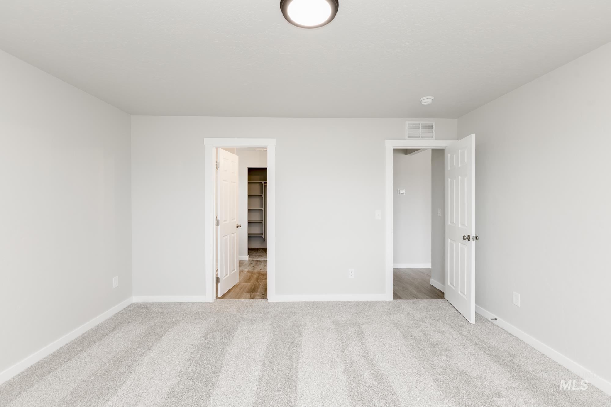 Unfurnished bedroom with light colored carpet and a walk in closet