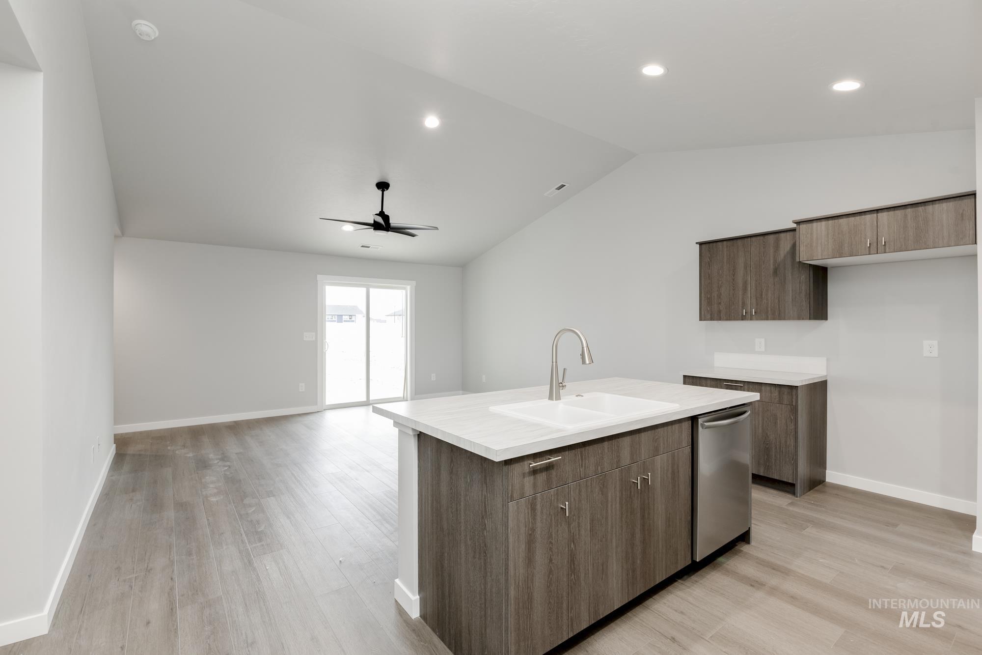 Kitchen with light countertops, modern cabinets, lofted ceiling, light wood finished floors, and open floor plan