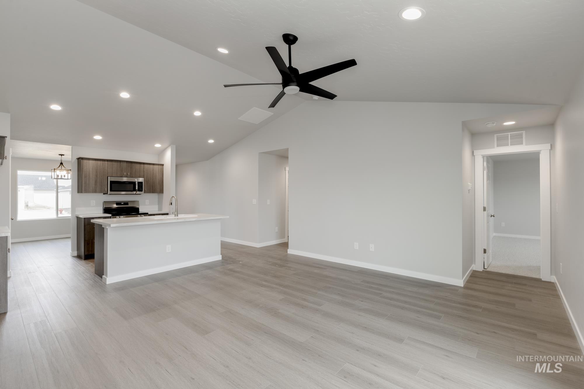 Kitchen with a center island with sink, recessed lighting, open floor plan, vaulted ceiling, and light wood-style flooring