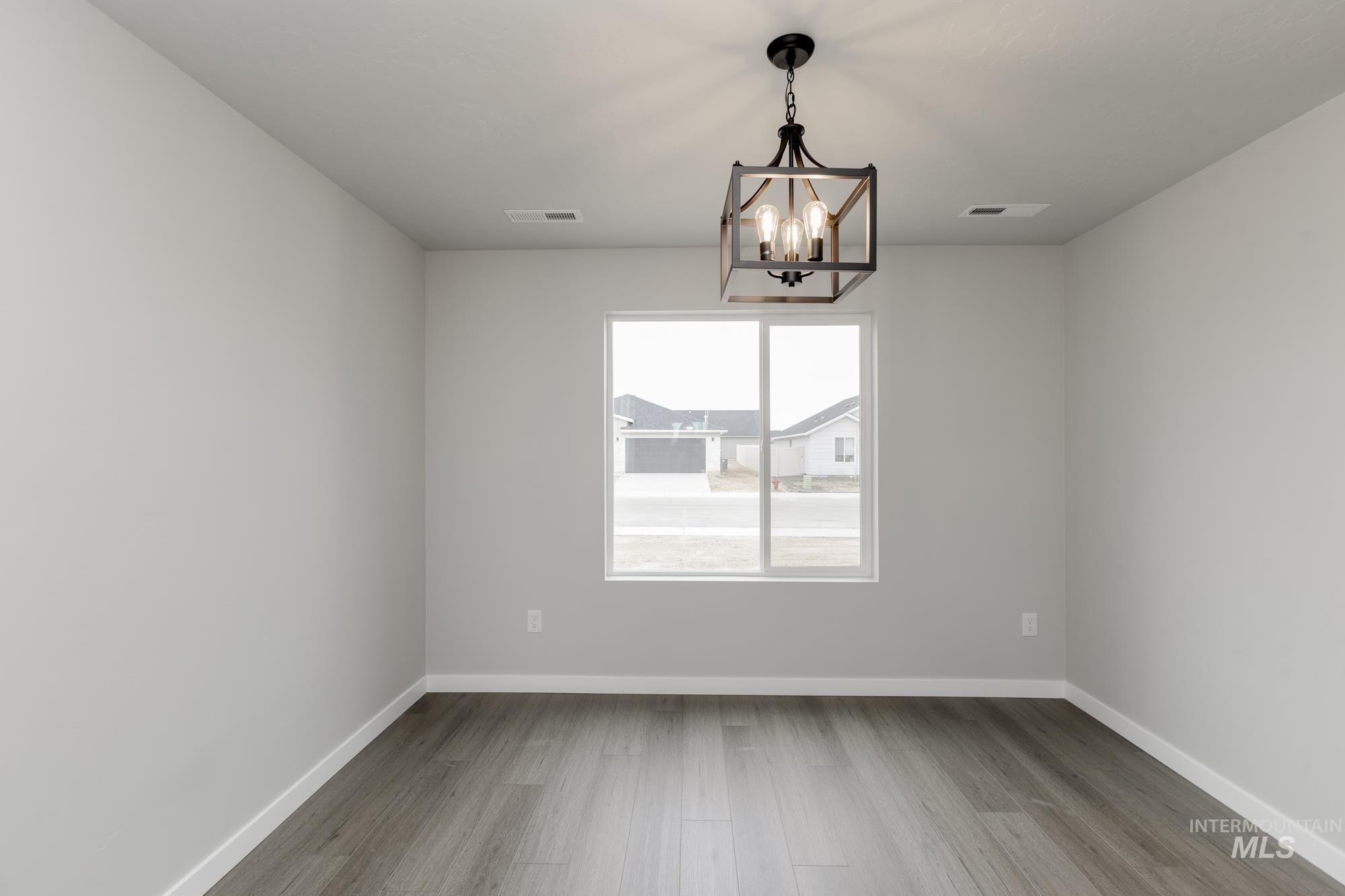 Empty room with light wood-style floors and a chandelier