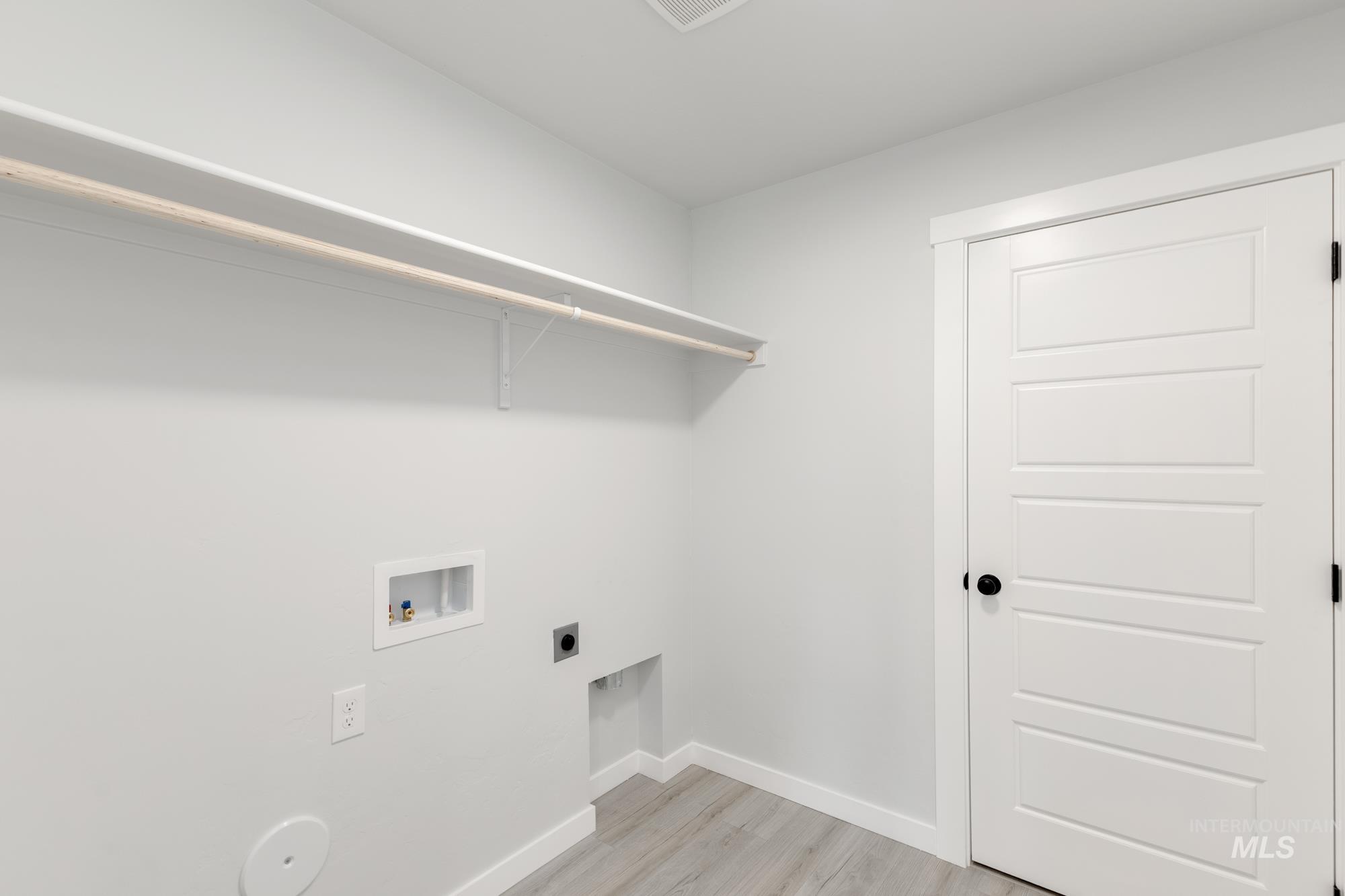 Laundry area with electric dryer hookup, light wood-style flooring, and washer hookup
