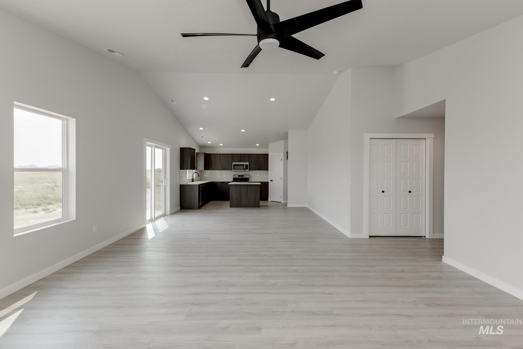 Unfurnished living room with recessed lighting, light wood-type flooring, ceiling fan, and high vaulted ceiling