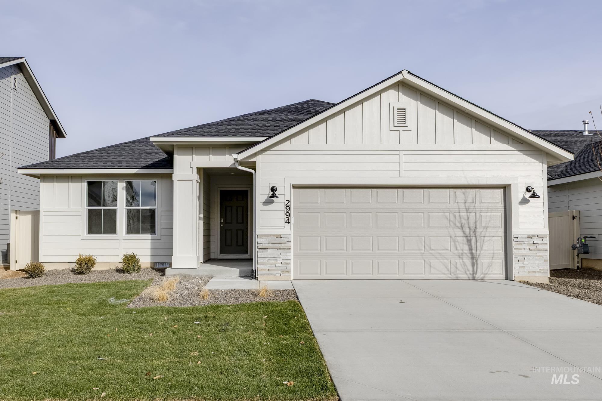 View of front facade with roof with shingles, board and batten siding, an attached garage, concrete driveway, and a front lawn