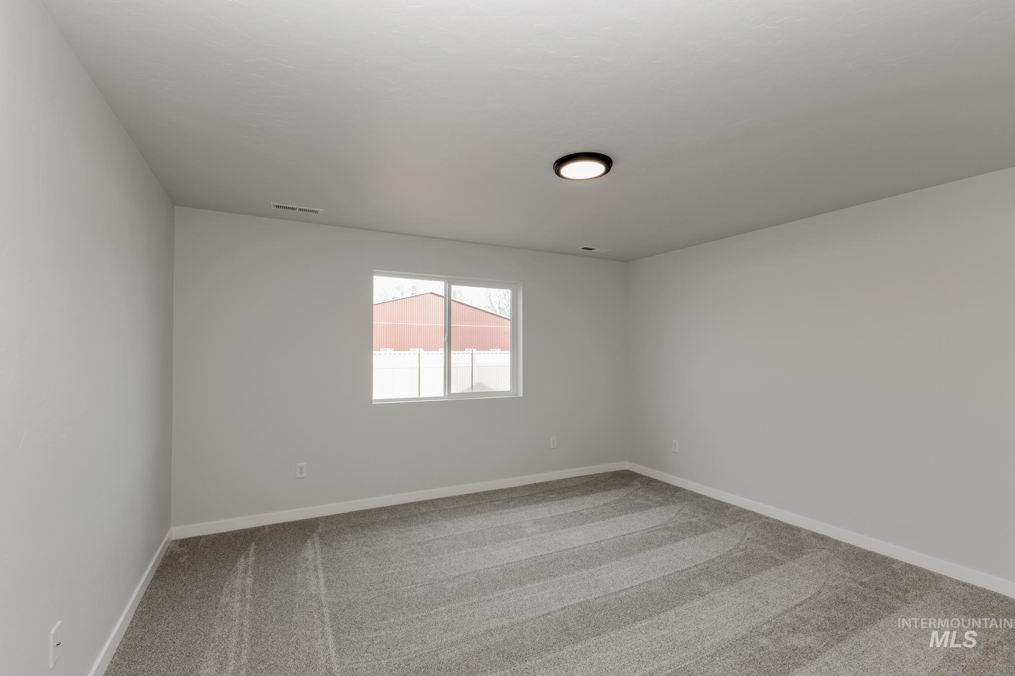 Spare room featuring light colored carpet and baseboards