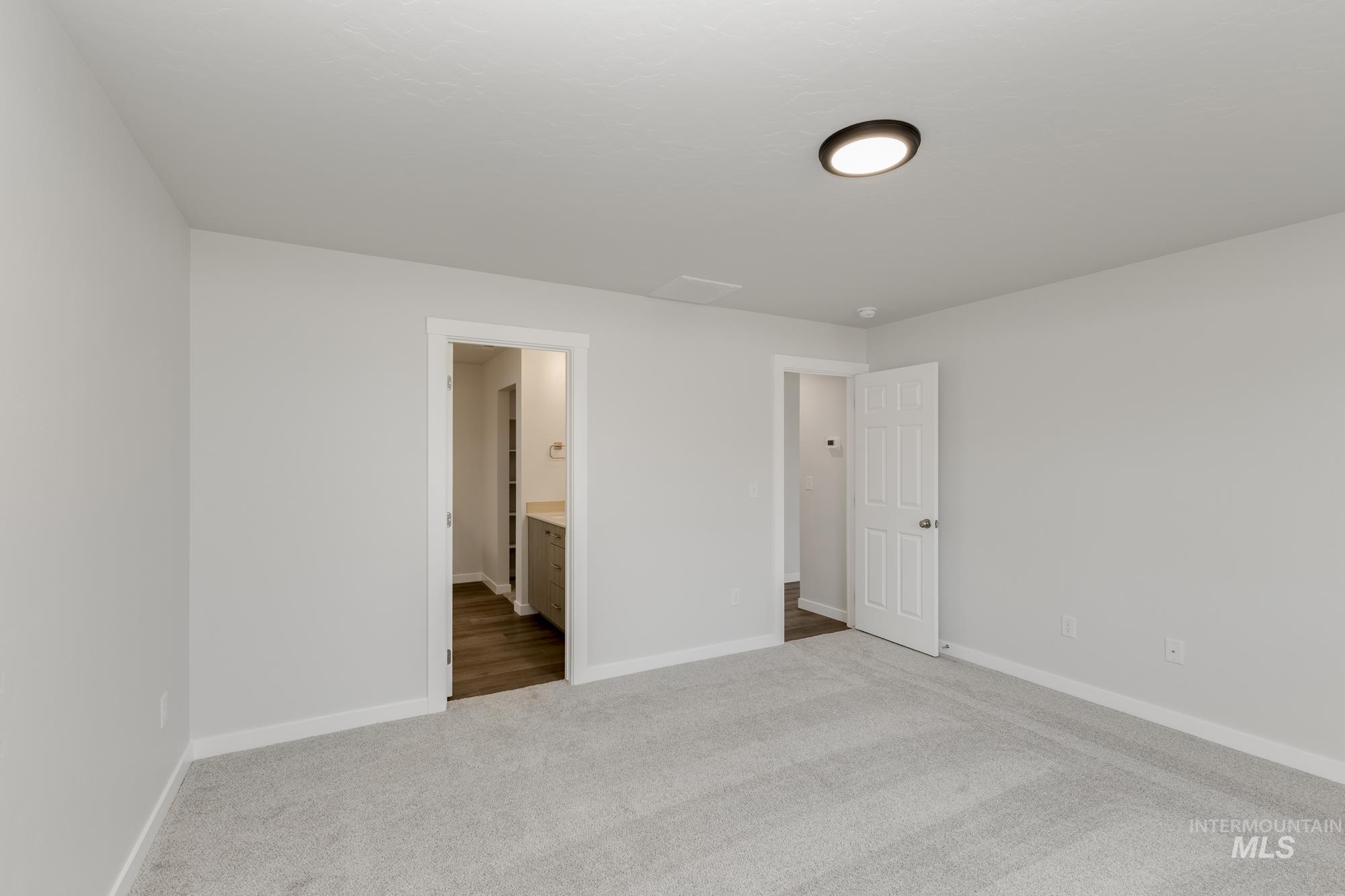 Unfurnished bedroom featuring light carpet and ensuite bath