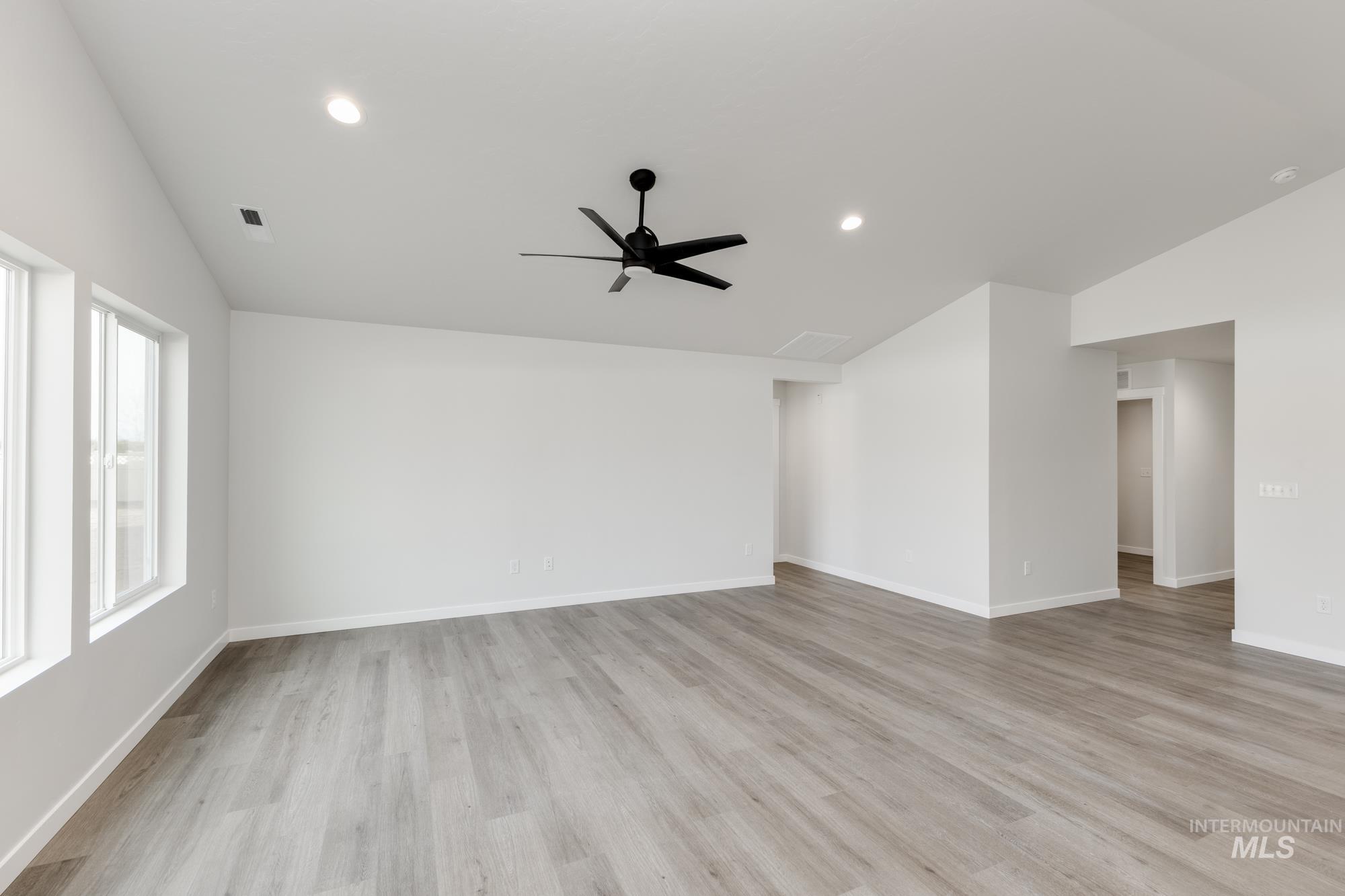 Unfurnished living room with lofted ceiling, light wood-style floors, a ceiling fan, and recessed lighting