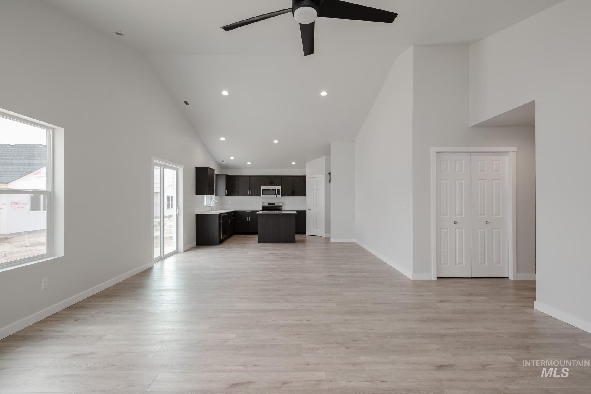 Unfurnished living room with high vaulted ceiling, recessed lighting, light wood-style flooring, and a ceiling fan