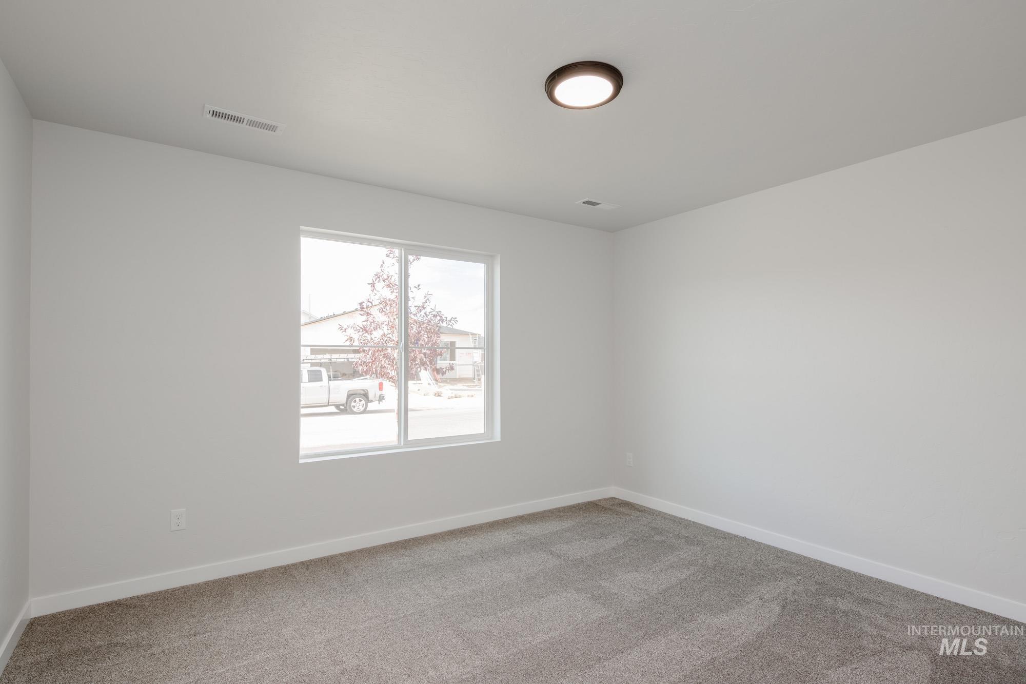 Spare room featuring light colored carpet and baseboards