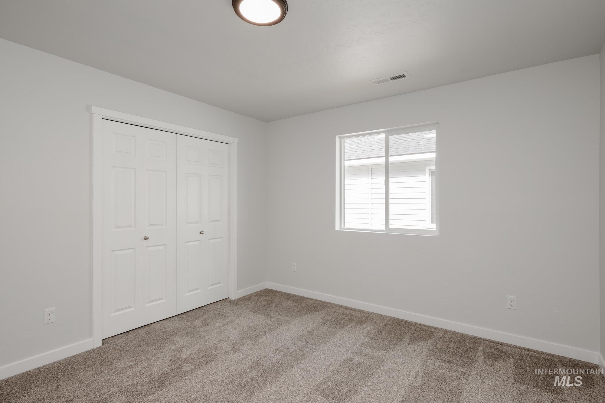 Unfurnished bedroom featuring light colored carpet and a closet