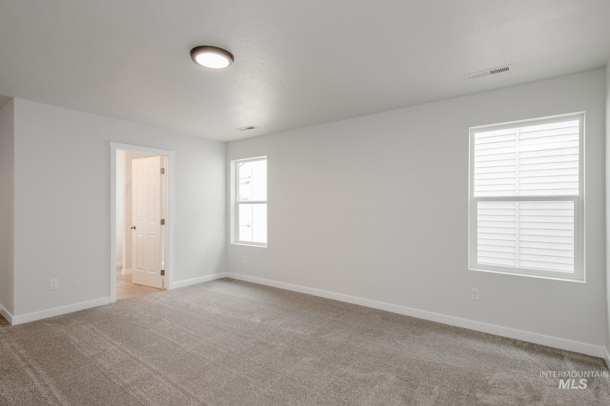 Empty room with light colored carpet and baseboards