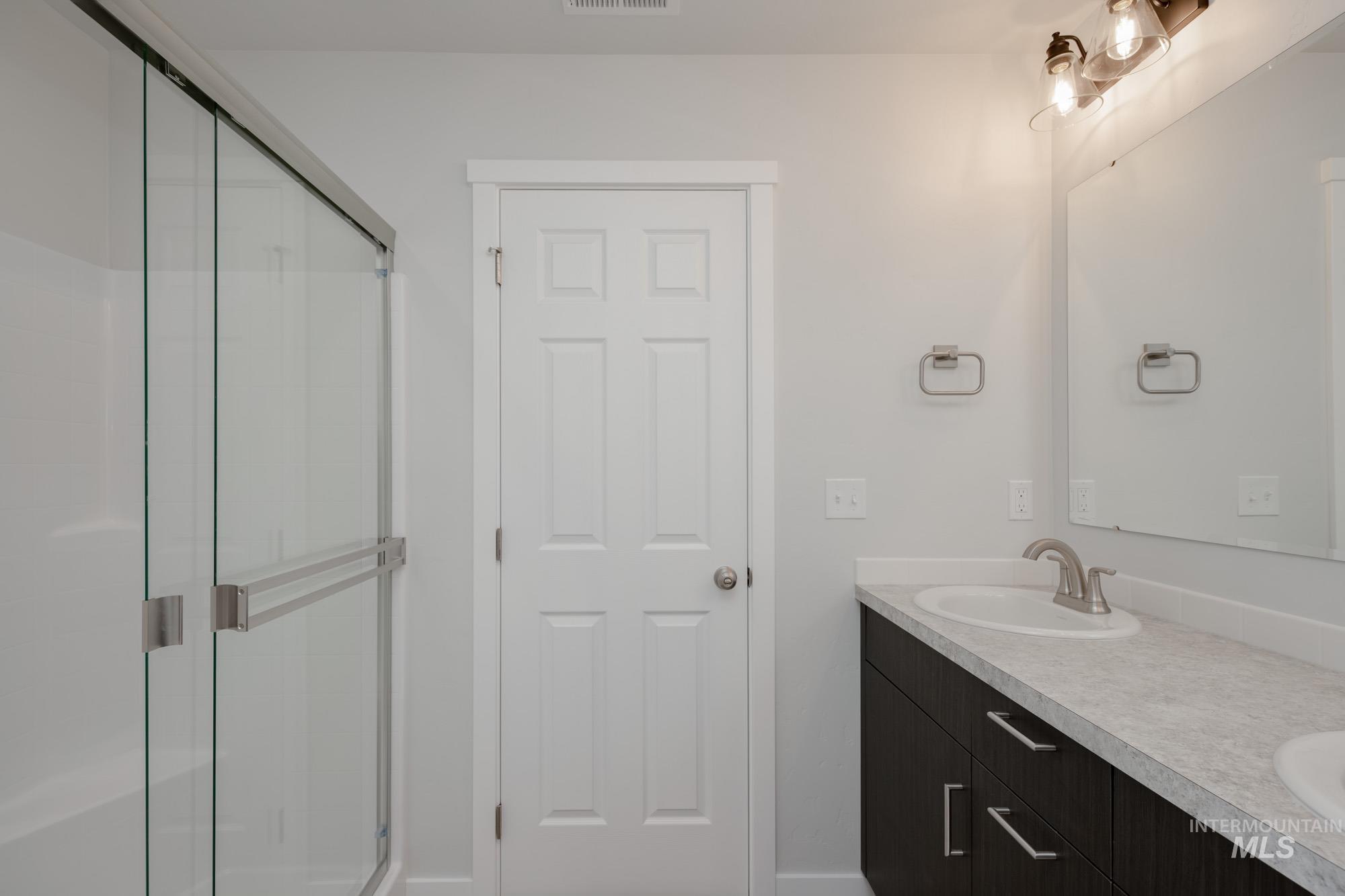 Full bath featuring double vanity and a stall shower