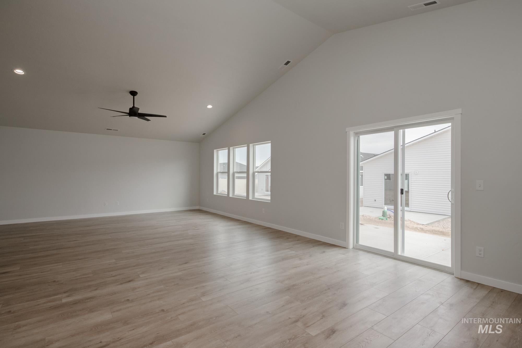 Empty room with high vaulted ceiling, light wood-type flooring, recessed lighting, and a ceiling fan