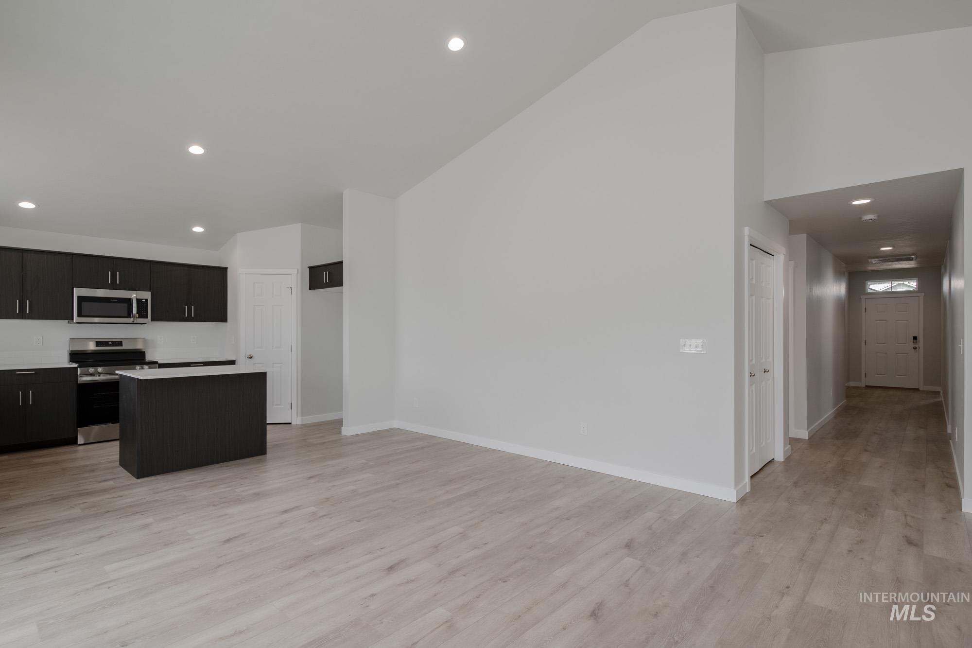 Kitchen with recessed lighting, a kitchen island, appliances with stainless steel finishes, light wood finished floors, and light countertops