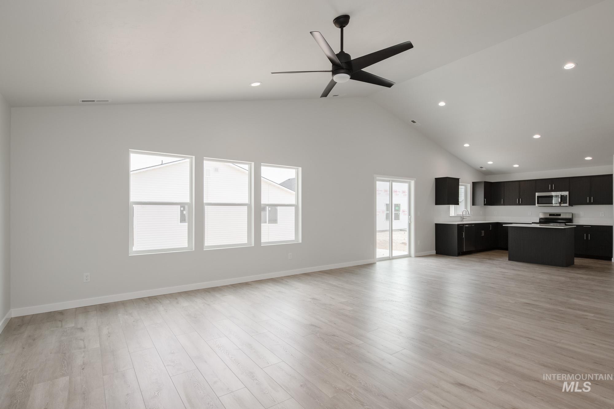 Unfurnished living room with light wood-style flooring, high vaulted ceiling, recessed lighting, and ceiling fan