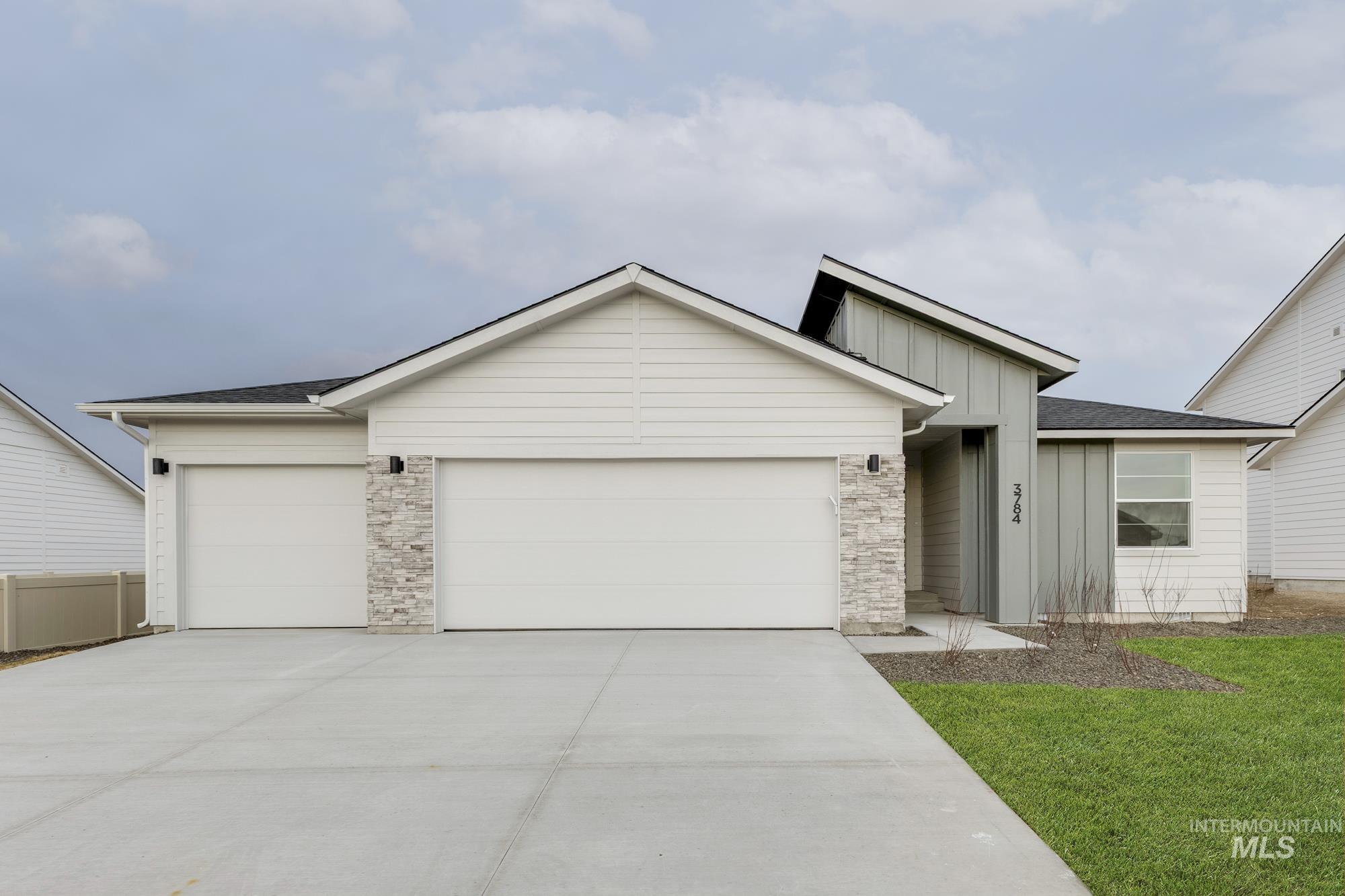 View of front of house featuring board and batten siding, an attached garage, concrete driveway, roof with shingles, and a front yard