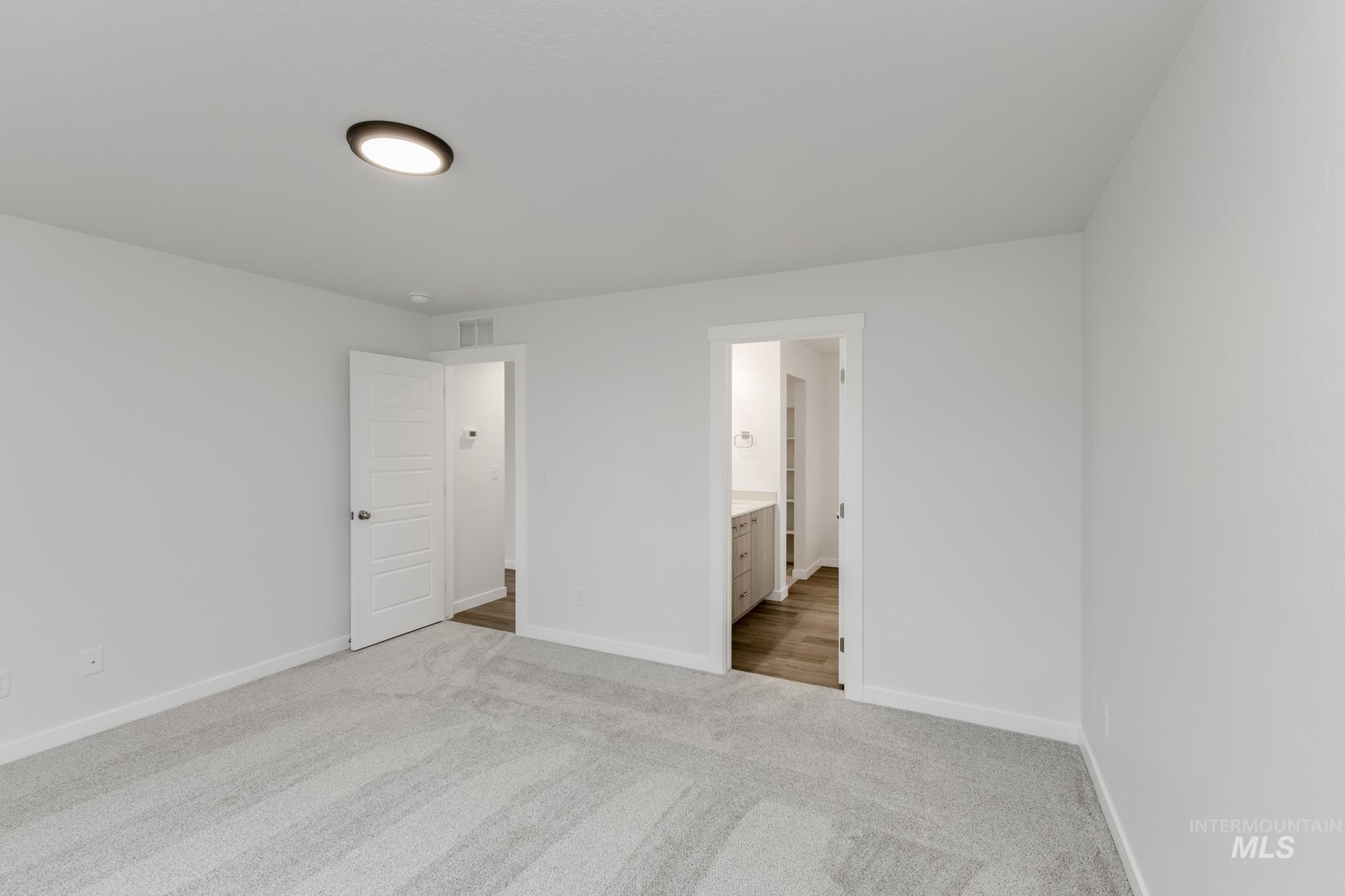 Unfurnished bedroom featuring light colored carpet and connected bathroom