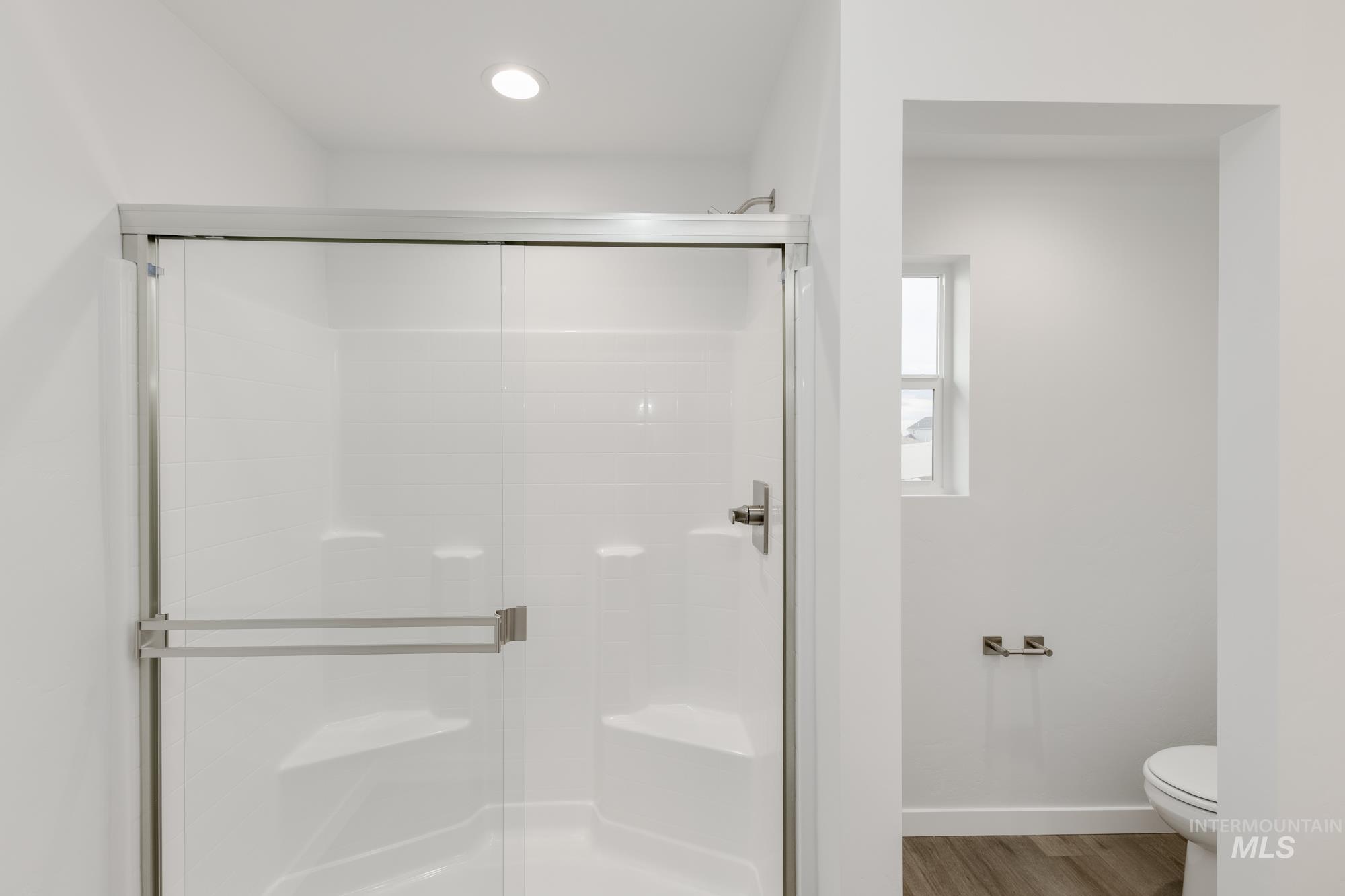 Full bathroom featuring a stall shower and wood finished floors