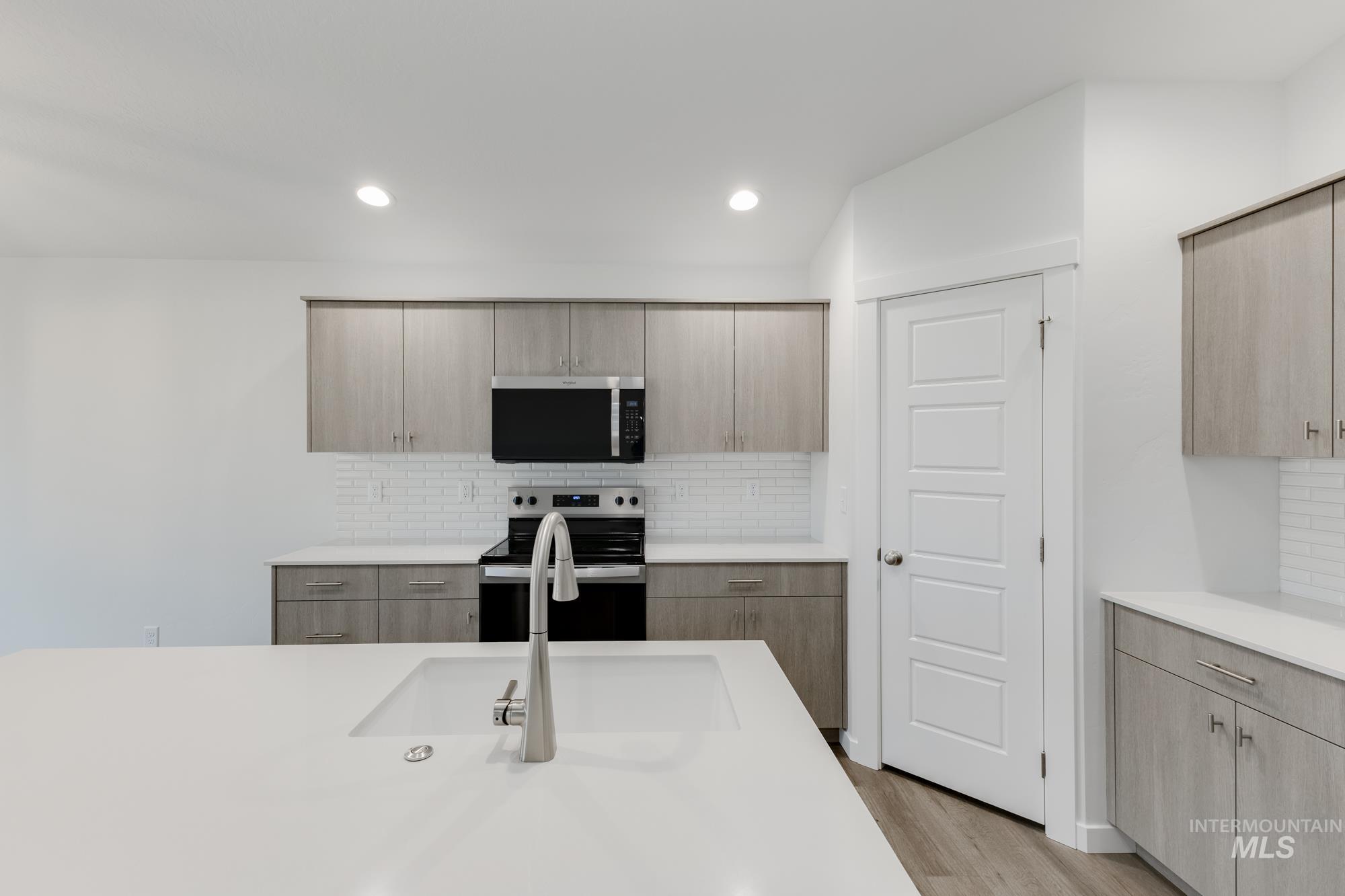 Kitchen featuring tasteful backsplash, modern cabinets, appliances with stainless steel finishes, light brown cabinetry, and recessed lighting