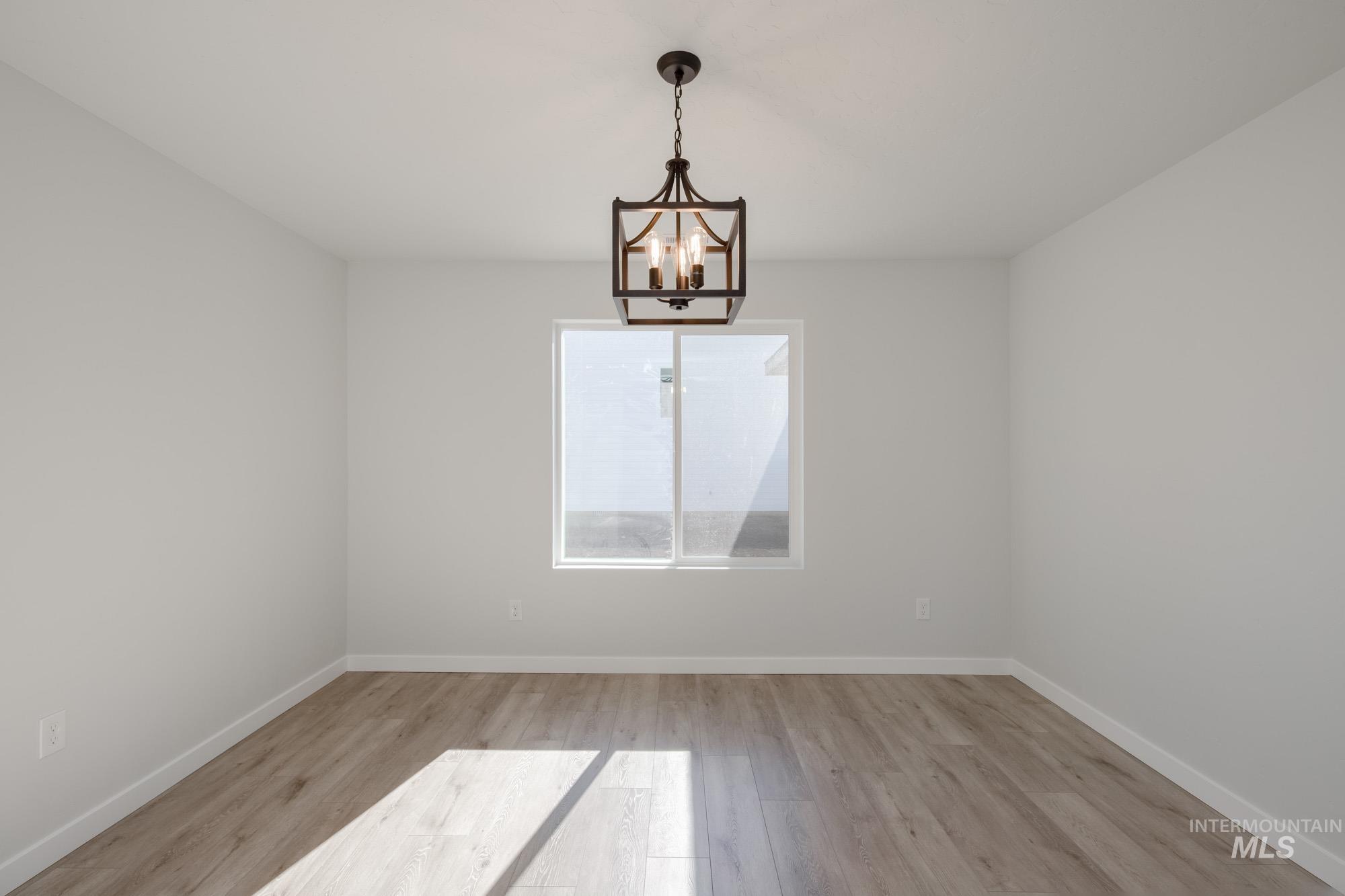 Unfurnished room featuring light wood-style floors and a chandelier