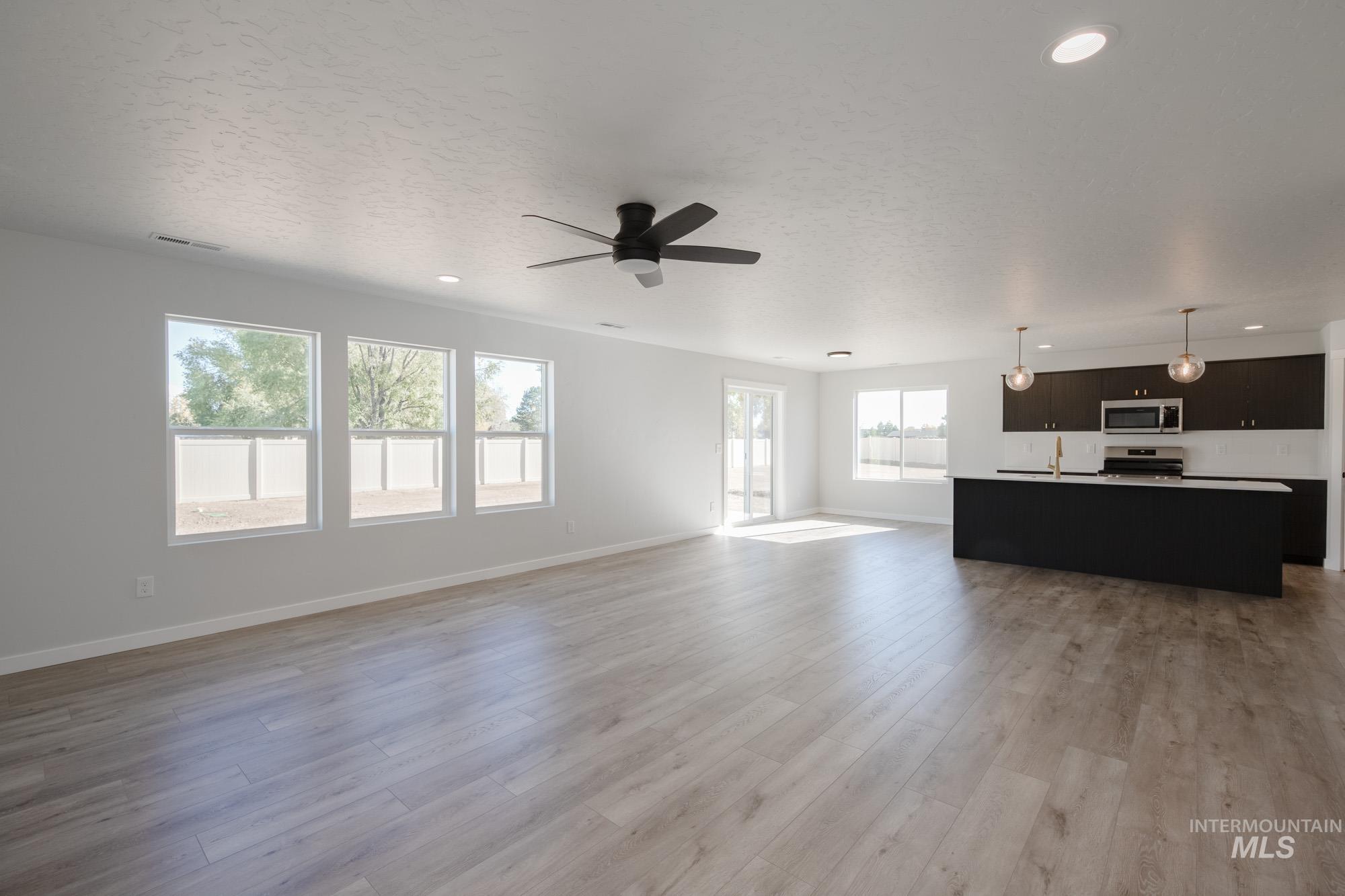 Unfurnished living room featuring recessed lighting, light wood-style flooring, a ceiling fan, and a textured ceiling