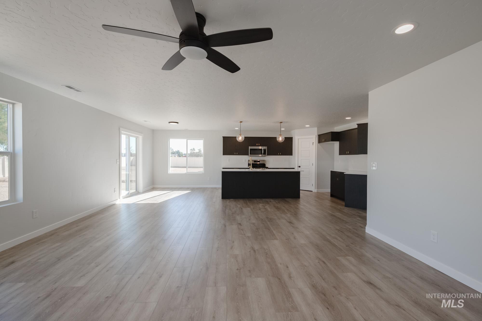 Unfurnished living room with light wood-style flooring, a ceiling fan, and recessed lighting