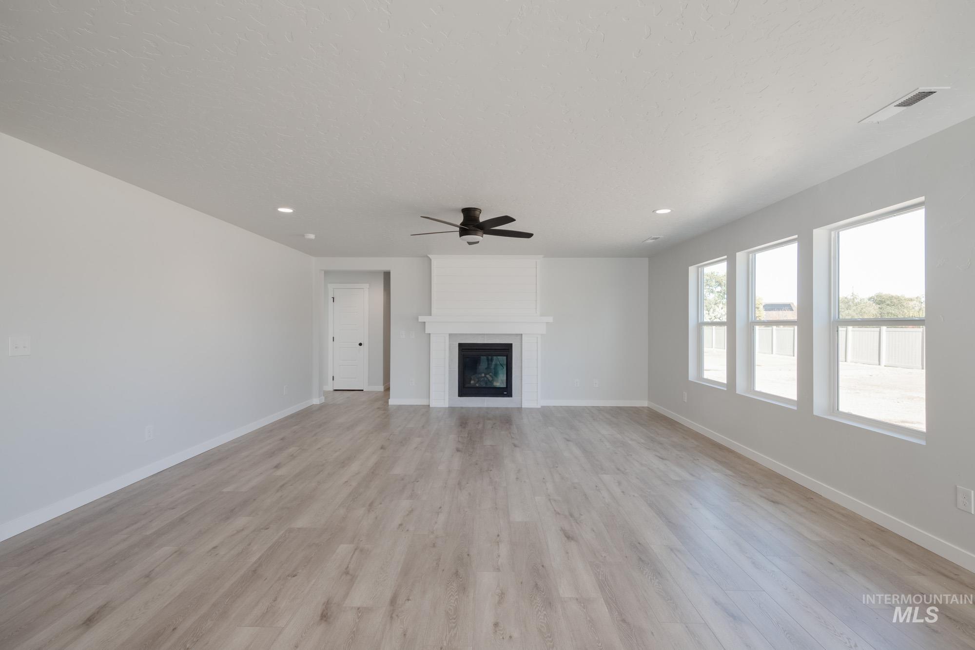 Unfurnished living room with a large fireplace, light wood-style flooring, a ceiling fan, and recessed lighting