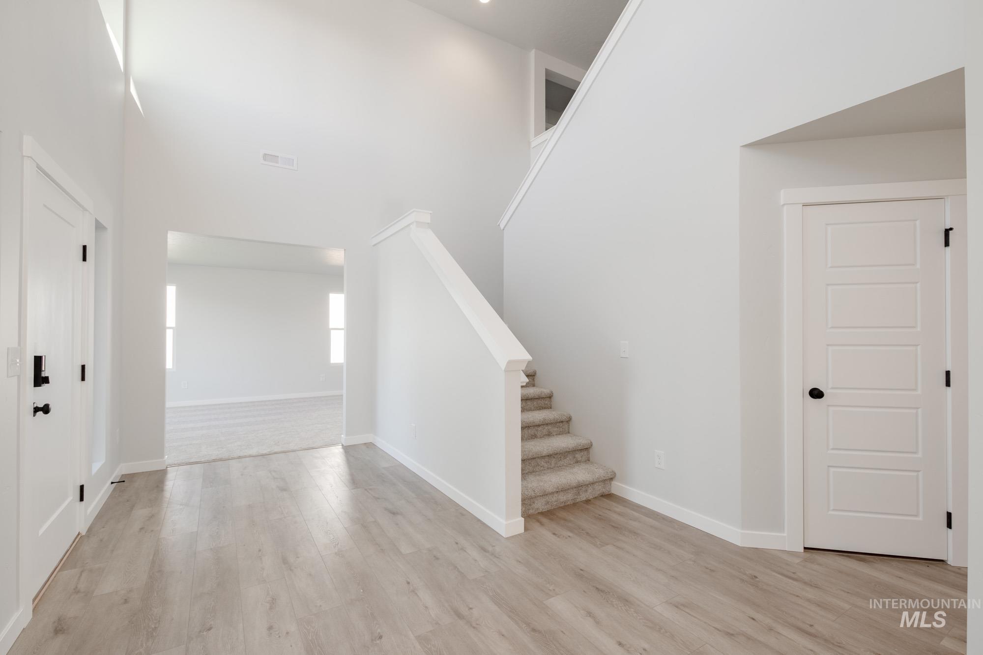 Entrance foyer featuring a high ceiling, stairs, and light wood-type flooring