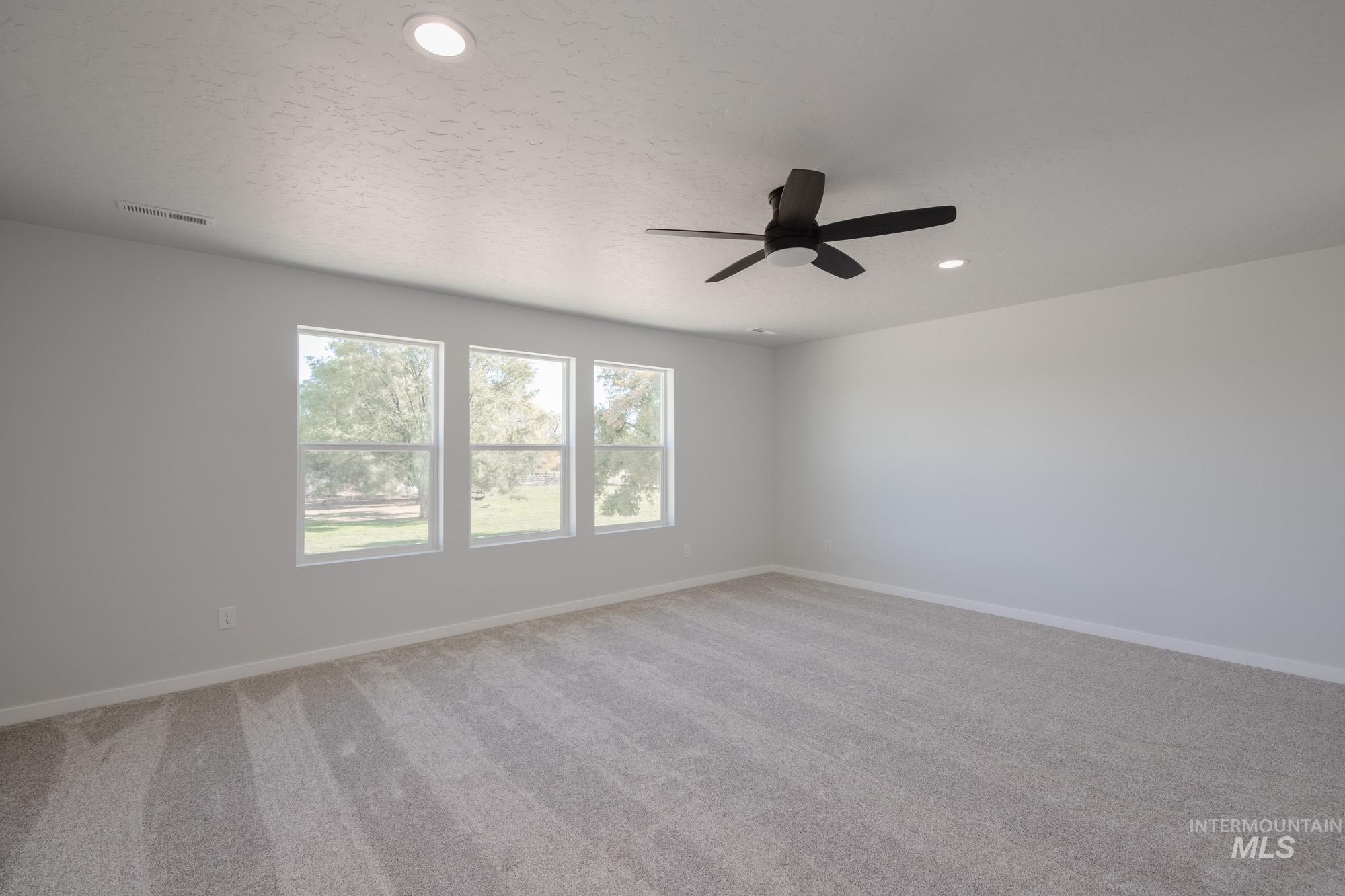 Empty room with light carpet, a textured ceiling, a ceiling fan, and recessed lighting