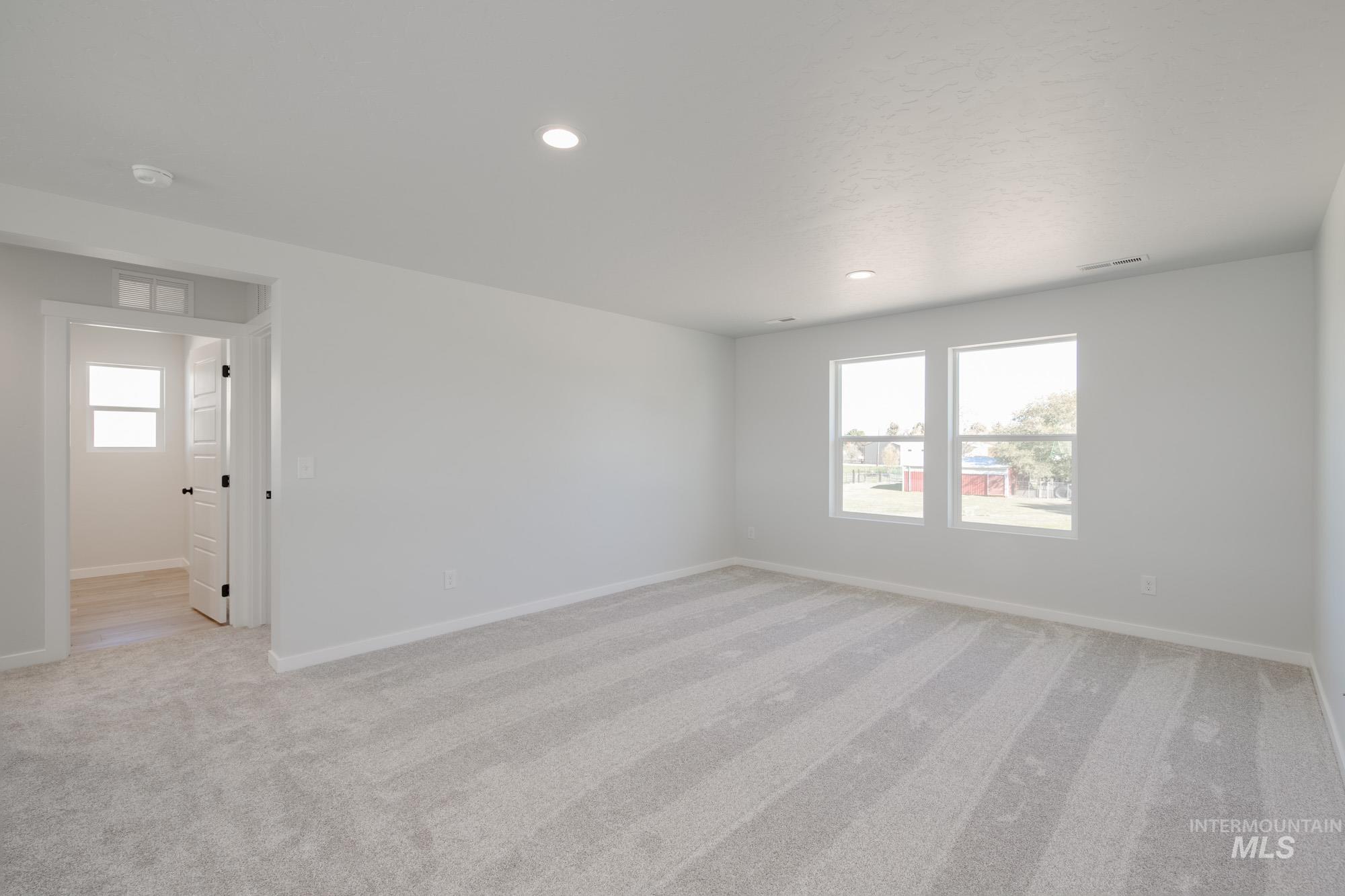 Spare room featuring light colored carpet, healthy amount of natural light, and recessed lighting