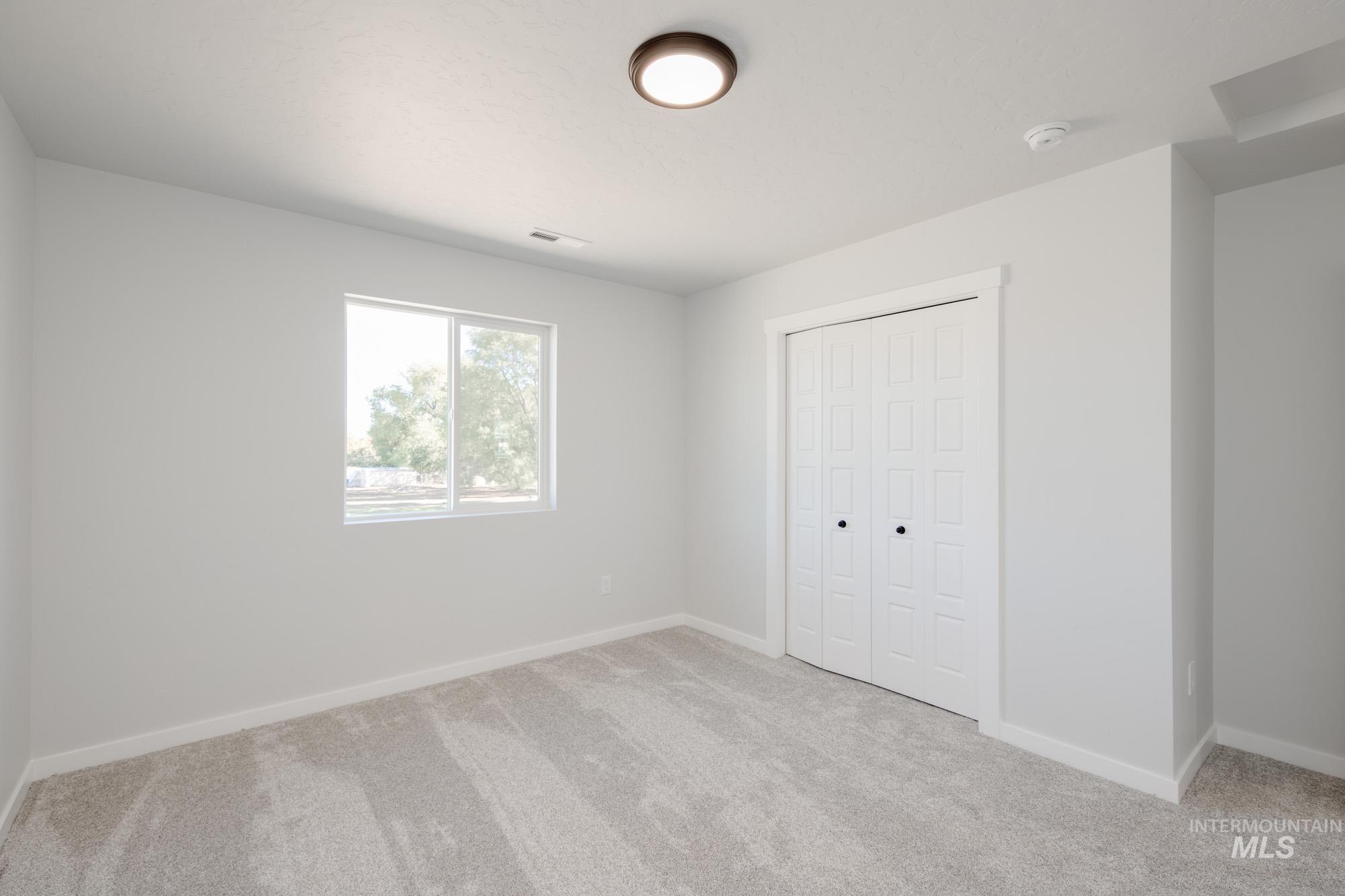 Unfurnished bedroom with light carpet and a closet