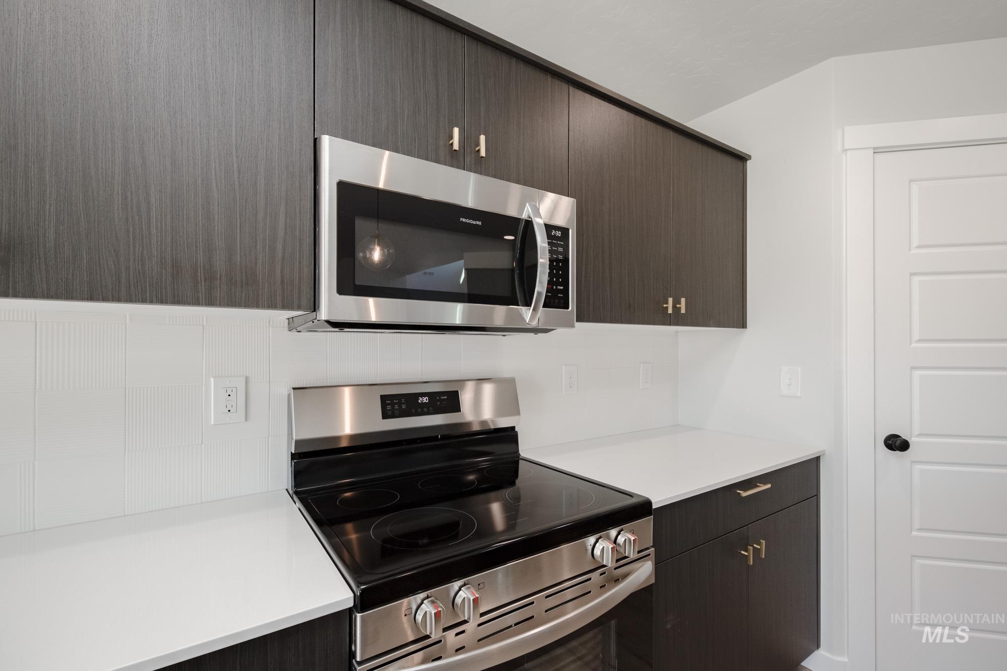 Kitchen with stainless steel appliances, tasteful backsplash, dark brown cabinetry, and modern cabinets