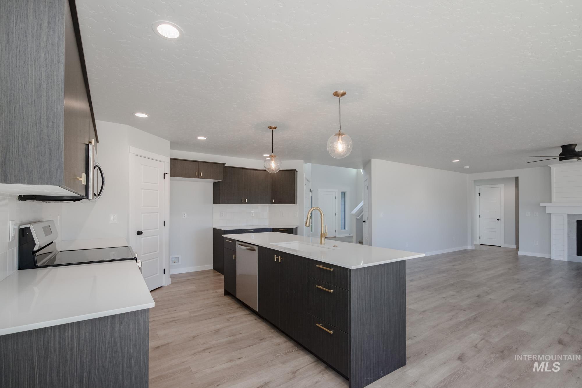 Kitchen with electric stove, light wood-style flooring, a kitchen island with sink, pendant lighting, and recessed lighting