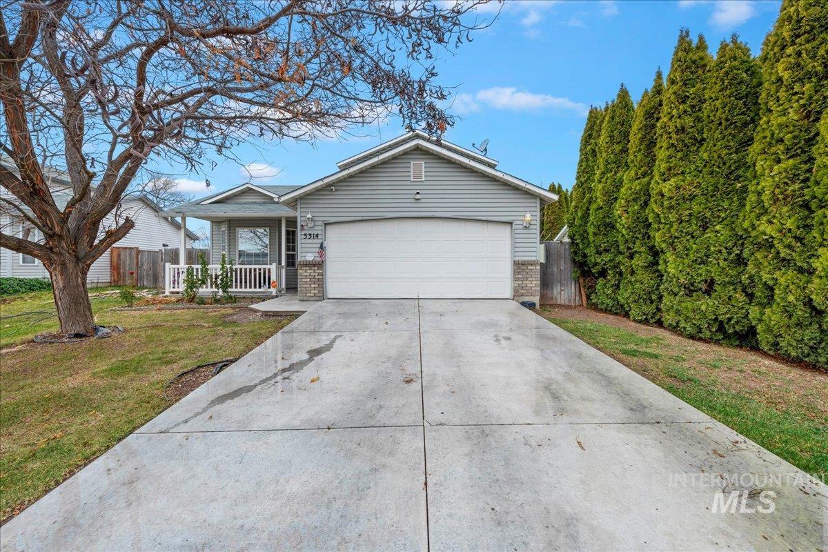 Single story home featuring concrete driveway, brick siding, a garage, and a porch