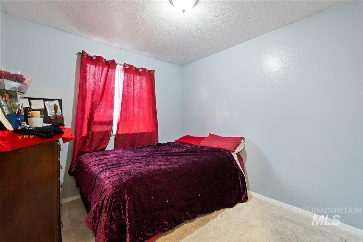 Carpeted bedroom with a textured ceiling and baseboards
