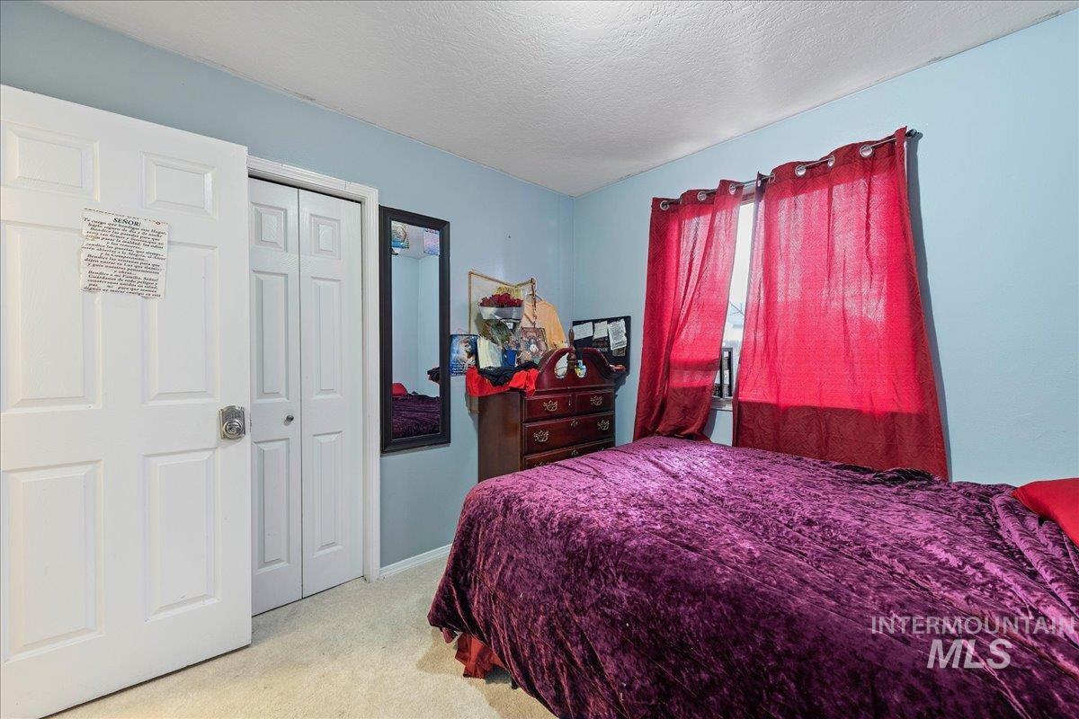Bedroom with carpet, a textured ceiling, and a closet