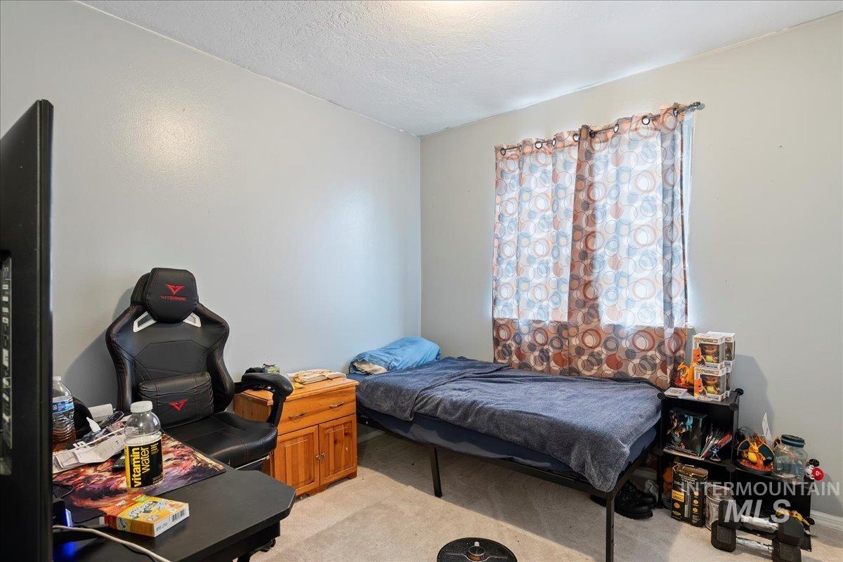 Bedroom featuring light carpet and a textured ceiling