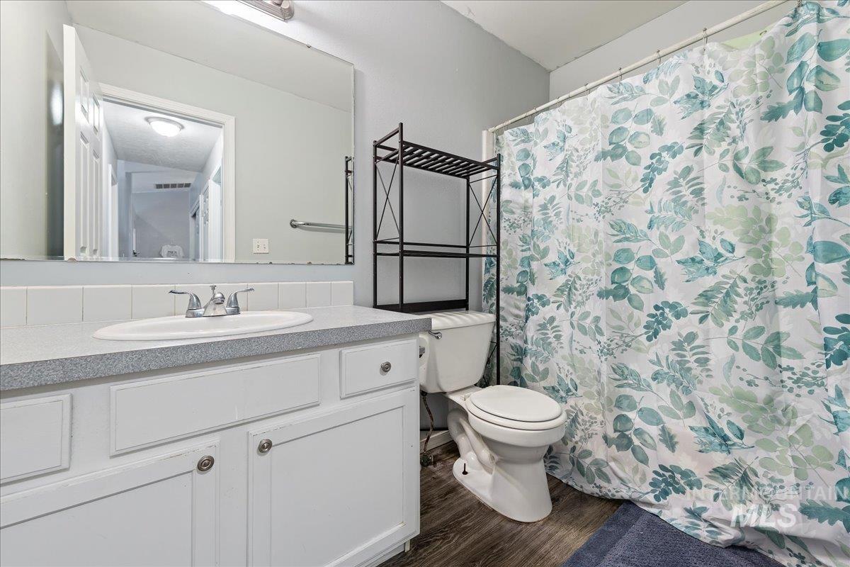 Bathroom with curtained shower, vanity, and dark wood finished floors