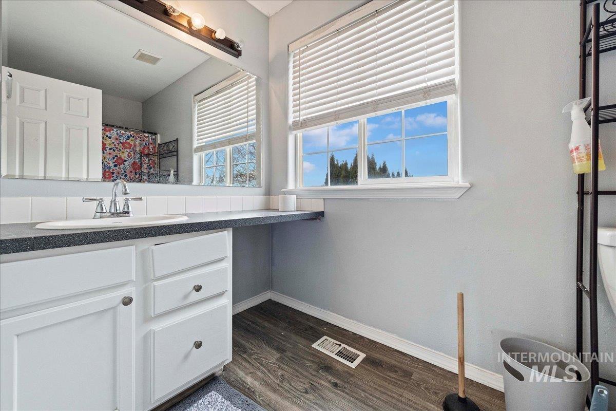 Full bath with vanity, a shower with curtain, and dark wood-style floors
