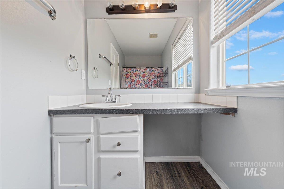 Bathroom with vanity, curtained shower, and dark wood-type flooring