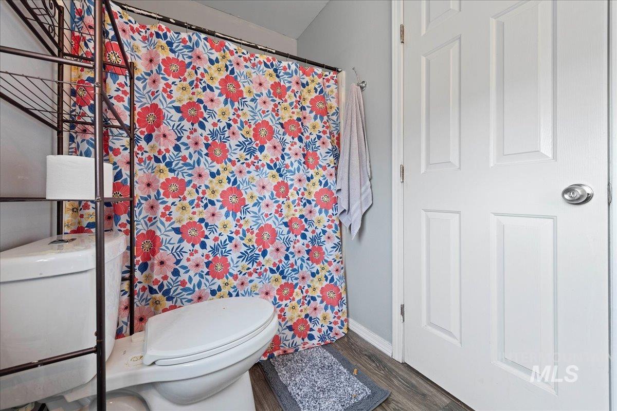 Bathroom with a shower with shower curtain and dark wood finished floors