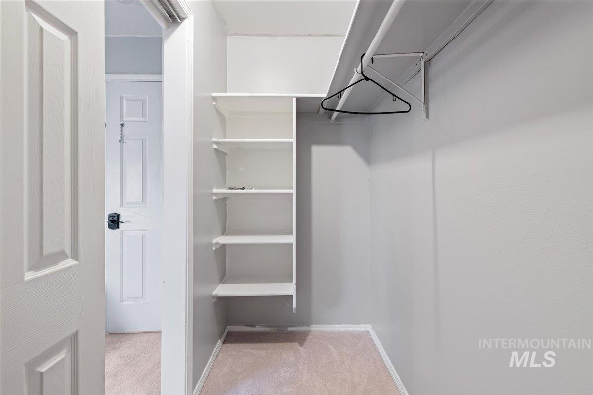 Walk in closet featuring light colored carpet