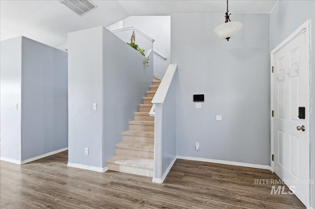 Entrance foyer featuring dark wood-style flooring and stairs