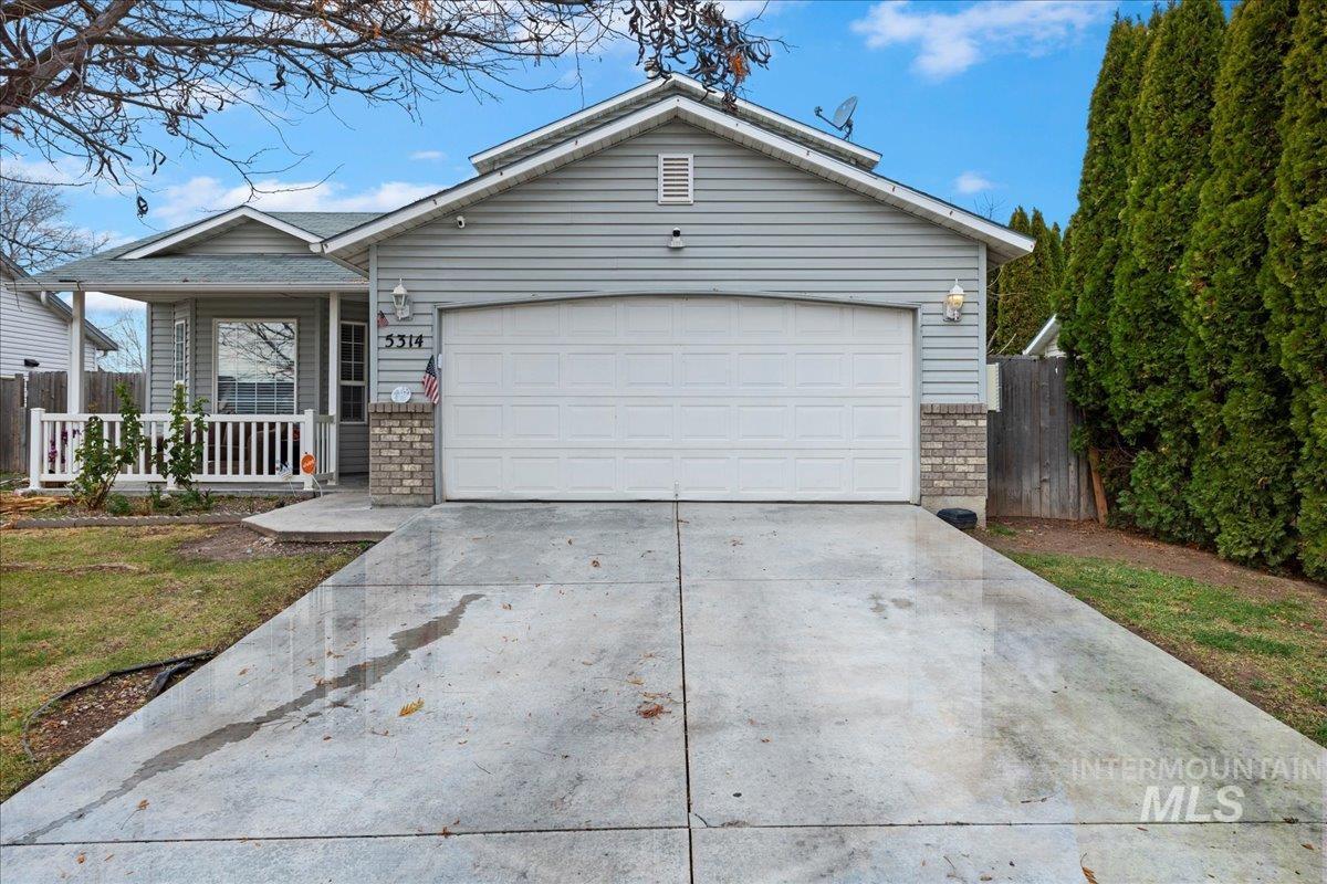 Single story home featuring driveway, a porch, brick siding, and a garage