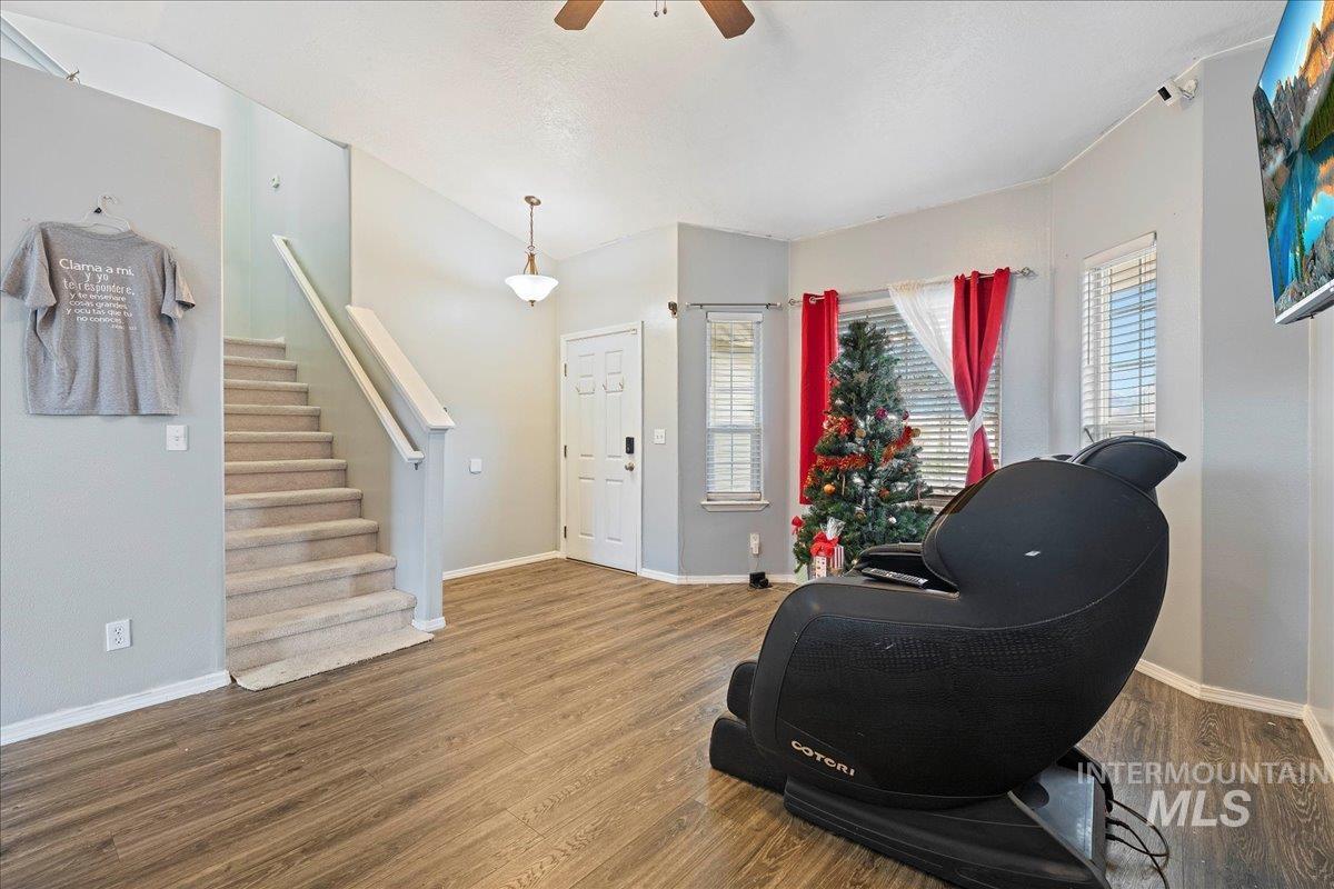 Living area with stairs, wood finished floors, and ceiling fan