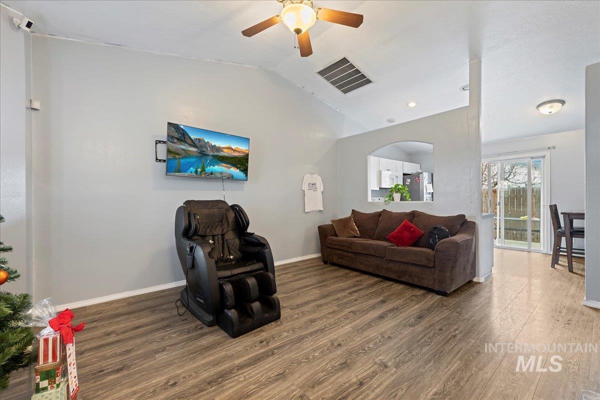 Living room featuring lofted ceiling, wood finished floors, and ceiling fan